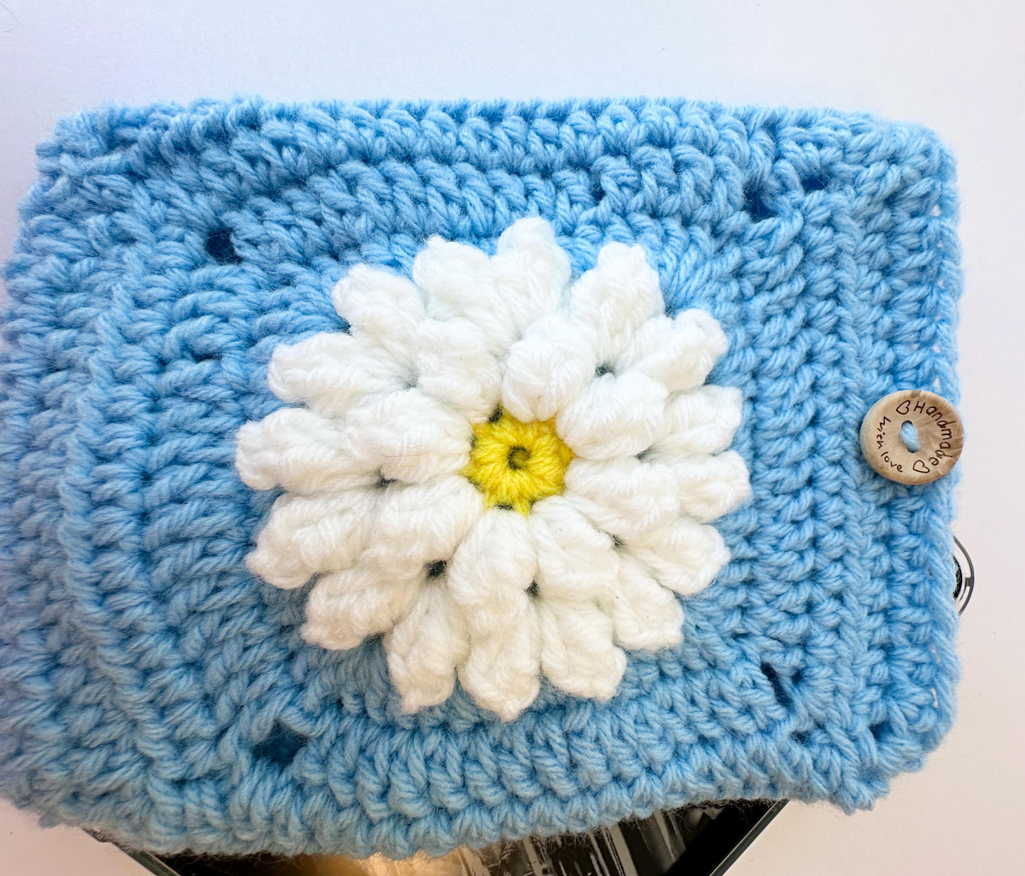 Blue Crocheted Kindle Sleeve with White Flower Granny Square & Wood Button, Handmade E-Reader Cover, Gift for Book Lovers measures 7.5 X 5.5