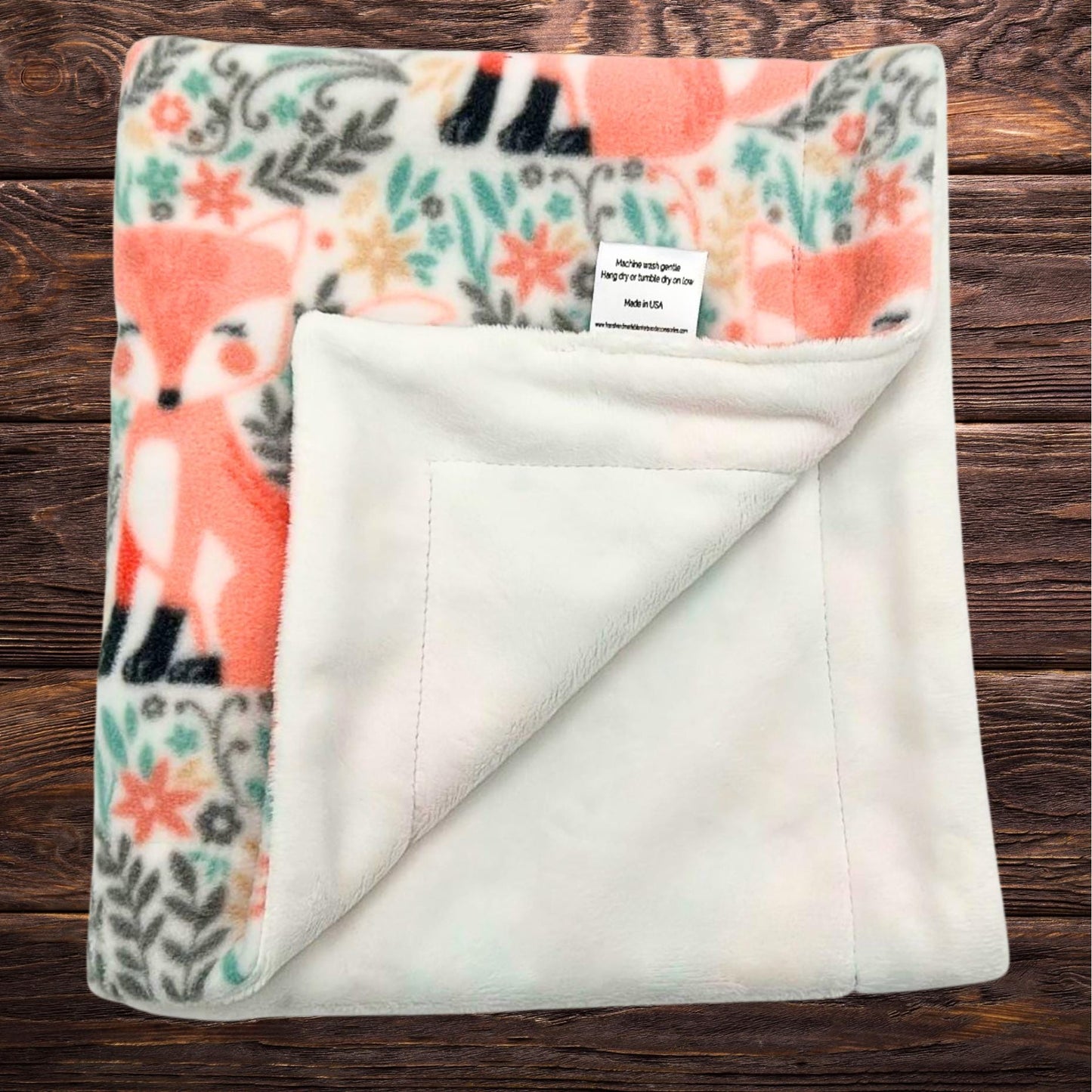 A cute pink fox print on one side of baby blanket with a soft white plush minky on the other side