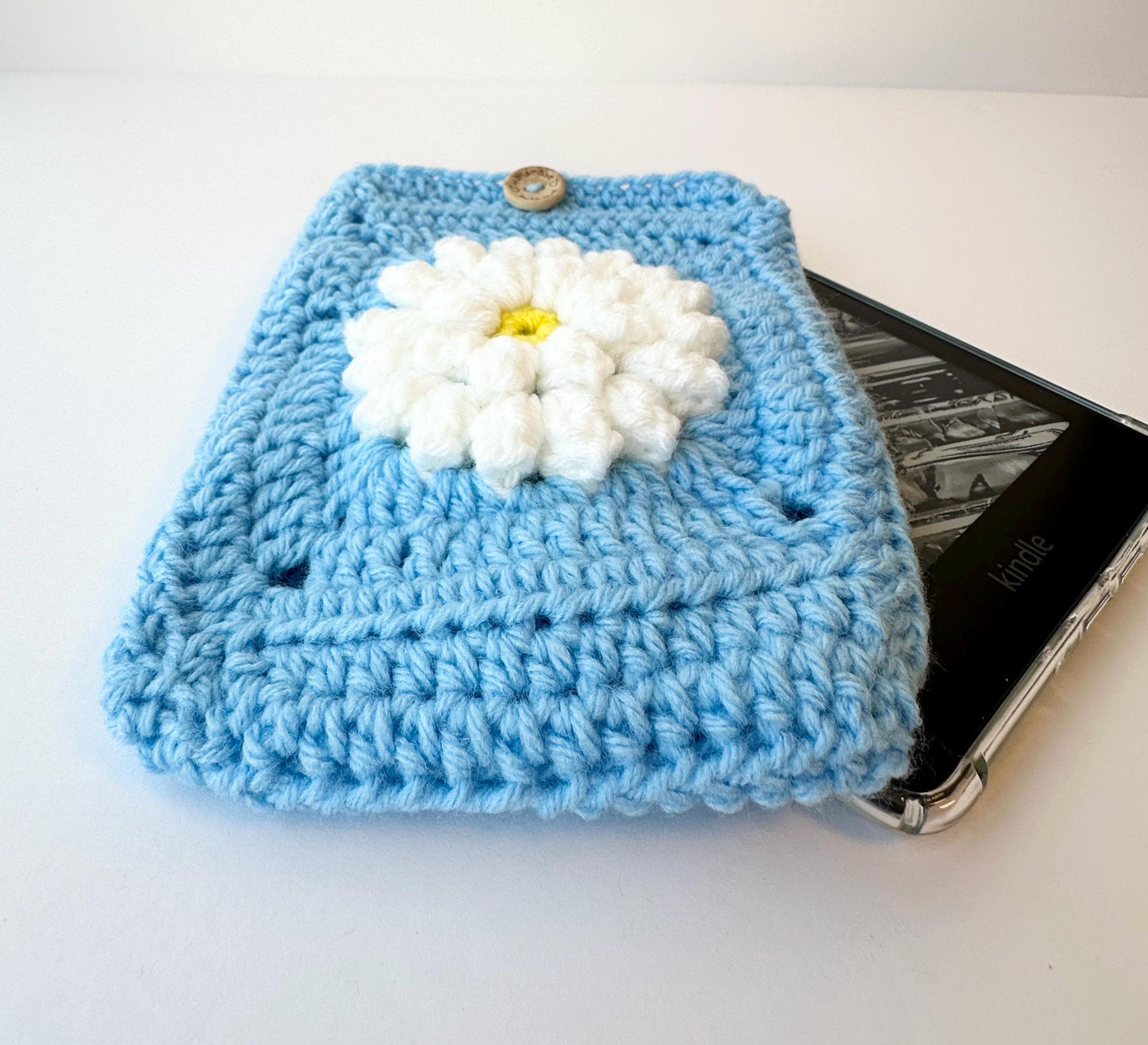 Blue Crocheted Kindle Sleeve with White Flower Granny Square & Wood Button, Handmade E-Reader Cover, Gift for Book Lovers measures 7.5 X 5.5