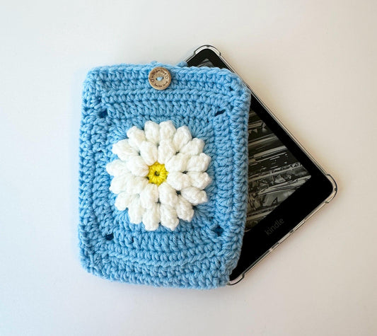 blue granny square crocheted kindle paperwhite sleeve featuring a raised white flower and wood button closure