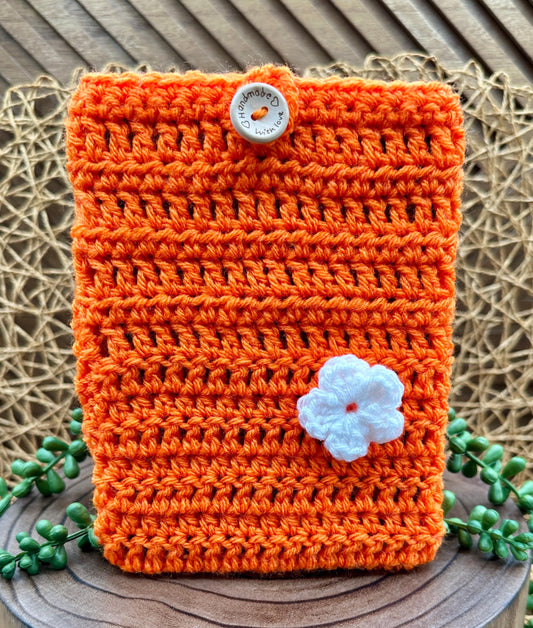 orange crocheted kindle paperwhite sleeve with a cute white flower and wood button closure