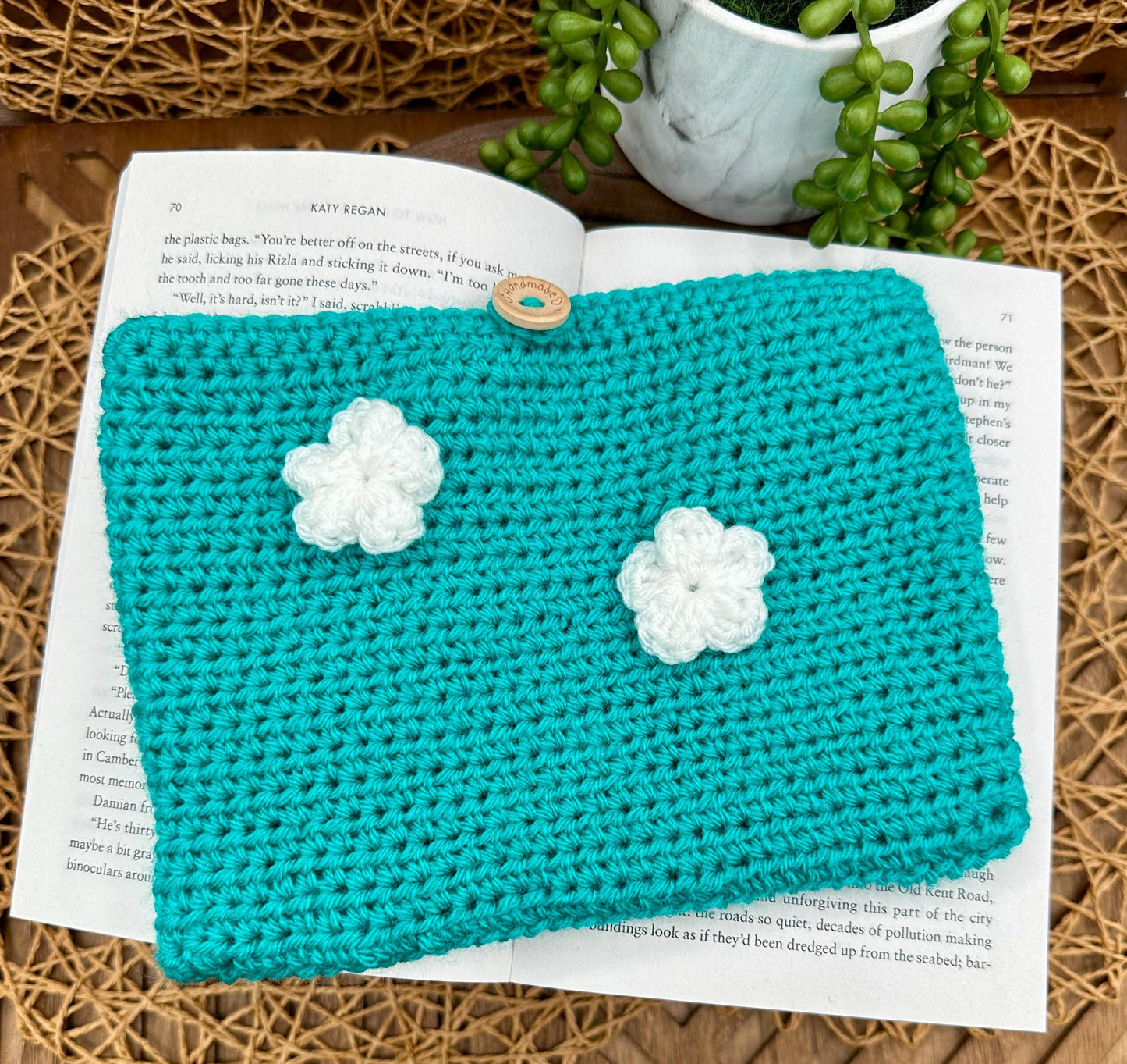 blue crocheted book sleeve with two white flowers