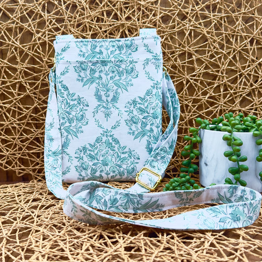 north south green cotton floral crossbody bag with adjustable and removable strap.  Had gold hardware and an exterior slip pocket