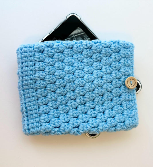 blue crocheted kindle paperwhite sleeve with a wood button closure