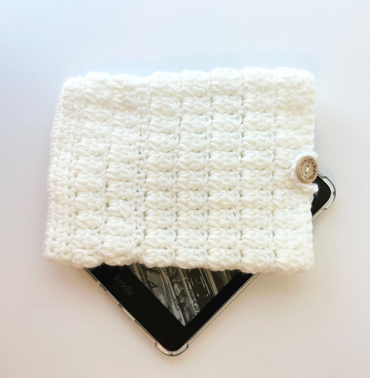 white crocheted kindle paperwhite sleeve with a wood button closure